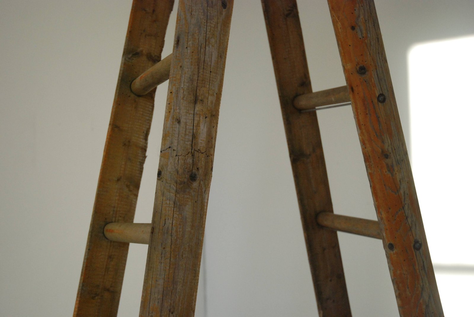 An installation with paintings, textiles and ladders is shown as a physical collage. The space they sit within is white and lit from above.